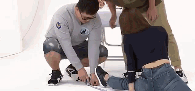 a man is measuring another man 's feet with a tape measure .