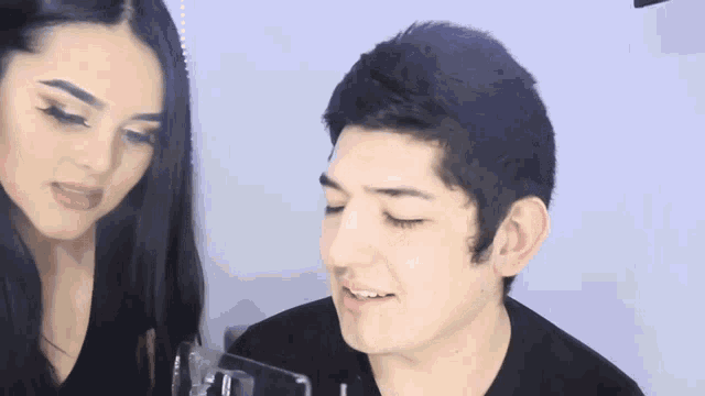 a man and a woman are standing next to each other and the woman is looking at the man 's face