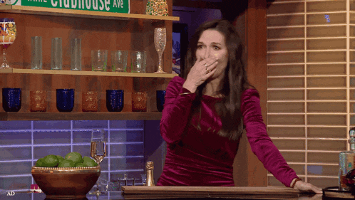 a woman covering her mouth in front of a sign that says clubhouse ave.