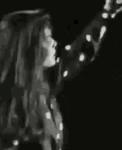 a woman in a polka dot shirt is dancing on a stage in a black and white photo .