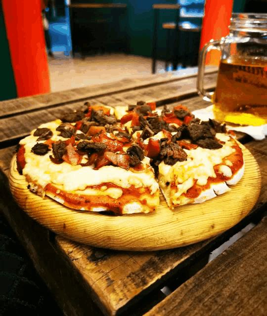 a pizza sitting on a wooden table next to a glass that says good