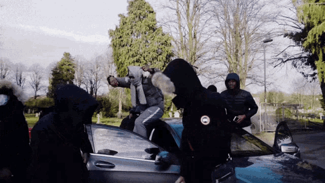 a man wearing a black canada goose jacket is getting into a car