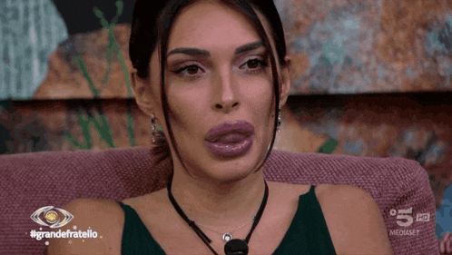a woman sitting on a couch with the words grandefratello on the bottom right