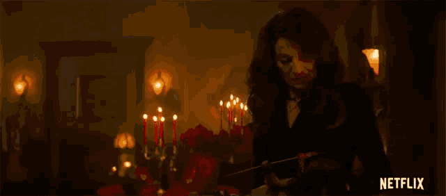 a woman in a black dress is standing in a room with candles .