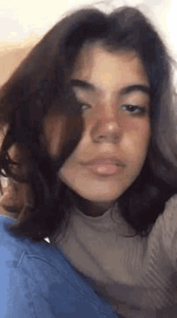 a close up of a girl 's face with a turtleneck sweater on .