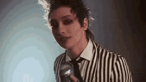 a young man in a striped suit and tie is singing into a microphone .