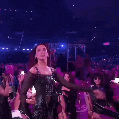 a woman is dancing in front of a crowd of people in a purple room .