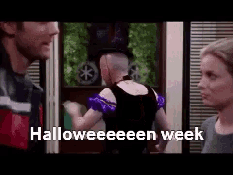 a woman in a halloween costume is standing in front of a man and a woman and says halloween week .