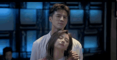 a man is putting his arm around a woman 's neck in a room .