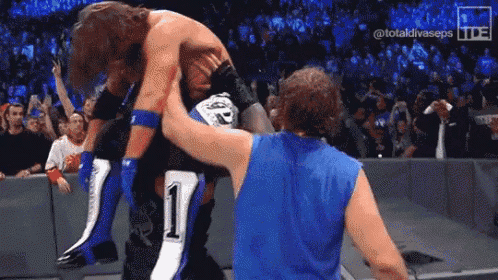 a wrestling match is taking place in front of a crowd .
