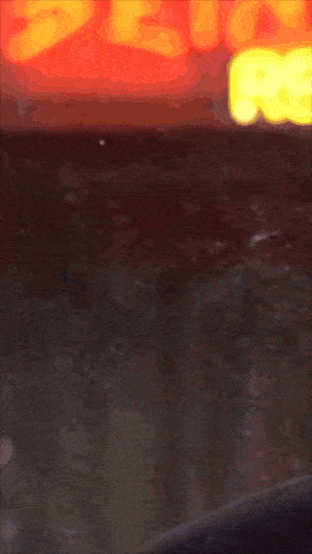 a close up of a man 's face with a red sign in the background