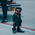 a man with a beard and sunglasses is standing next to a car .