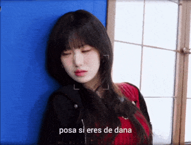 a woman leaning against a blue wall with the words posa si eres de dana written below her