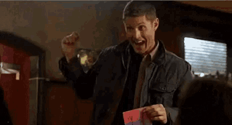 a man in a jacket and tie is holding a valentine 's day card .