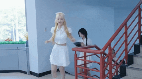 a woman in a white dress is walking down the stairs