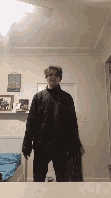a young man in a black jacket stands in front of a mirror