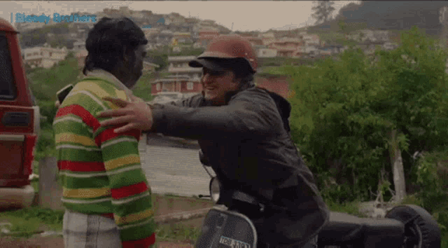 a man on a scooter is hugging another man and the words bloody brothers are on the bottom