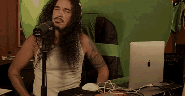 a man is singing into a microphone in front of a laptop