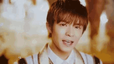 a close up of a young man wearing a white shirt and a white jacket .