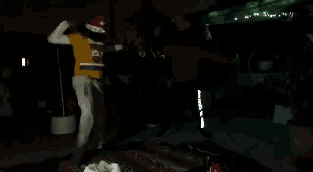 a person wearing a santa hat is dancing in a dark room .