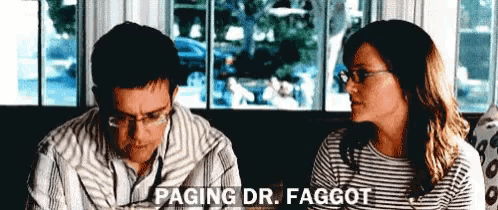 a man and a woman are sitting in front of a window and the woman is saying paging dr. faggot