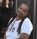 a woman wearing a white t-shirt with dreadlocks is smiling .