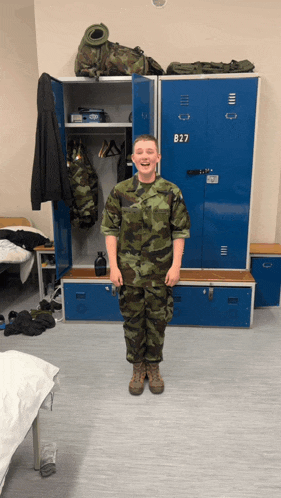 a man in a military uniform is standing in front of lockers with the number b27 on them