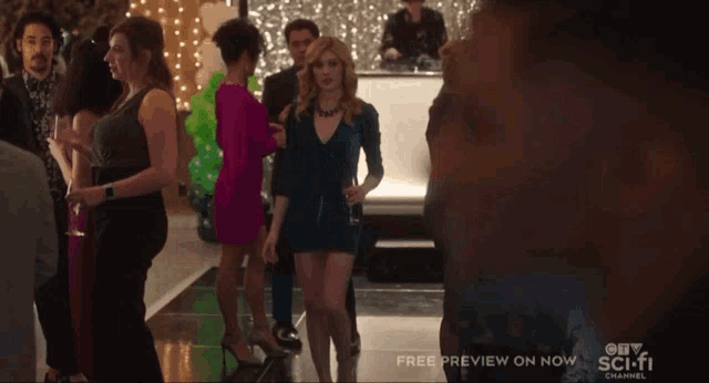 a woman in a blue dress stands in a crowd of people with a free preview on now
