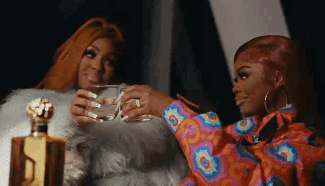 two women are sitting next to each other drinking alcohol .