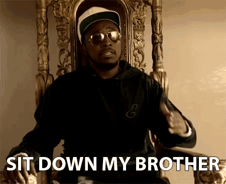 a man wearing sunglasses and a hat is sitting in a chair with the words sit down my brother above him