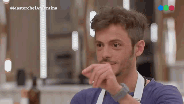 a man in a blue shirt and white apron is on a tv show called masterchef argentina