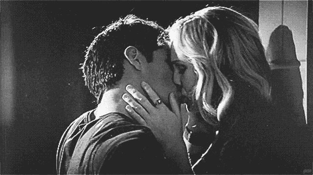 a black and white photo of a man and woman kissing