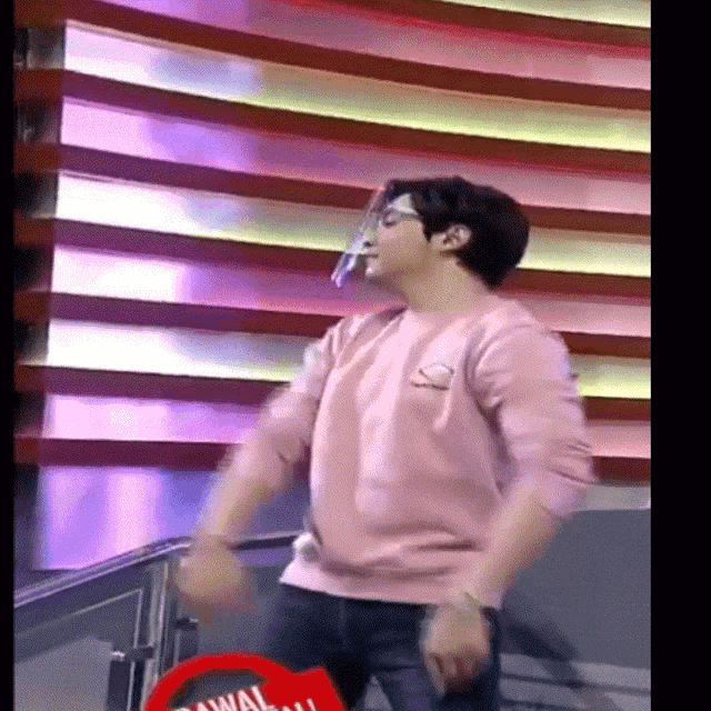 a man in a pink shirt is dancing in front of a sign that says ' awa ' on it
