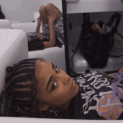 a girl with braids is laying on a couch wearing a shirt that says ' nsfw '