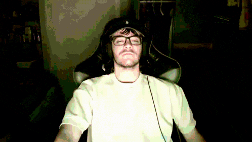a man wearing glasses and headphones sitting in a chair