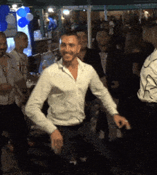 a man in a white shirt is dancing in front of a crowd of people
