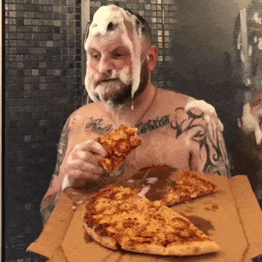 a shirtless man with a tattoo on his arm eating pizza with foam on his face