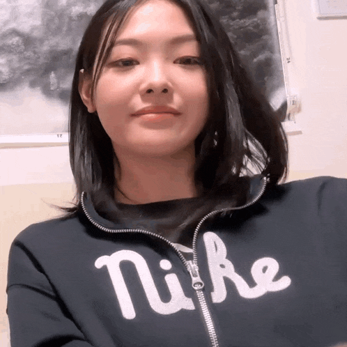a woman wearing a black nike sweatshirt is looking at the camera