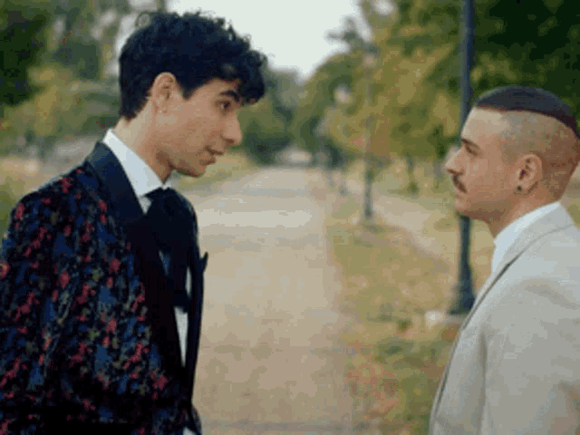two men in suits are standing next to each other and talking
