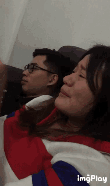 a man and a woman are sitting on a couch and the woman is crying while the man looks at her