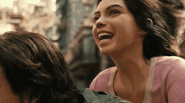 a woman in a pink shirt is laughing with a man
