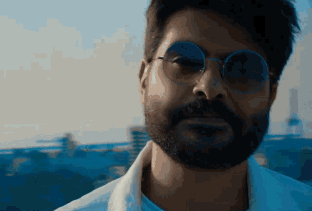 a man with a beard wearing round sunglasses