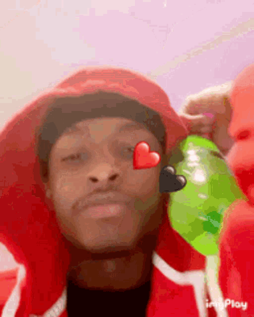 a man wearing a red hat and a red jacket has a heart on his eye .