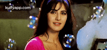 a woman in a pink top is surrounded by soap bubbles .