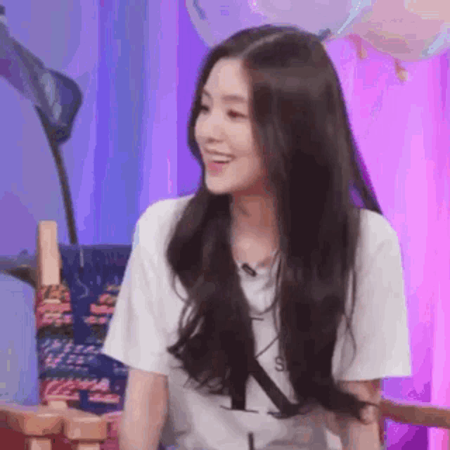 a woman with long hair is wearing a white t-shirt and smiling .