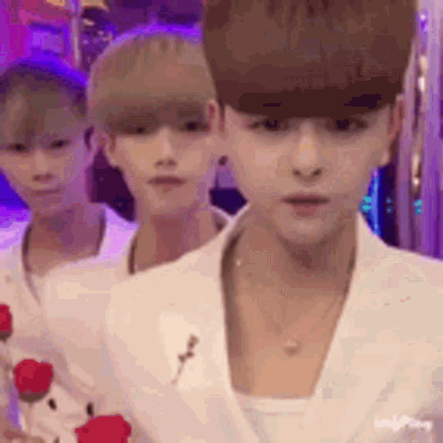 a group of young men are standing next to each other in a line holding red roses .