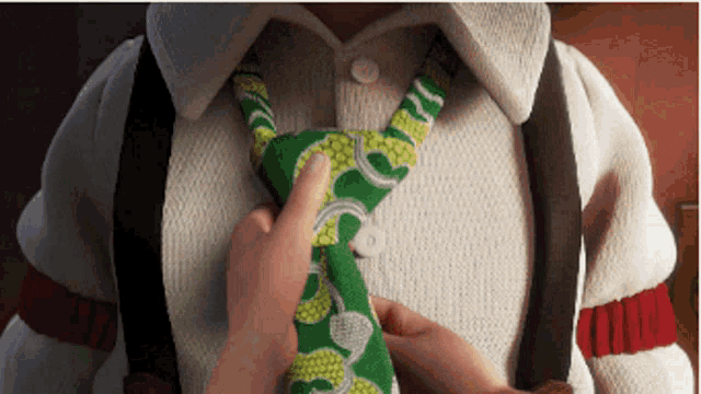 a close up of a person tying a green and white tie