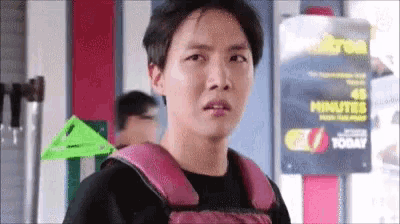 a young man wearing a pink backpack is standing in front of a sign that says `` 48 minutes '' .