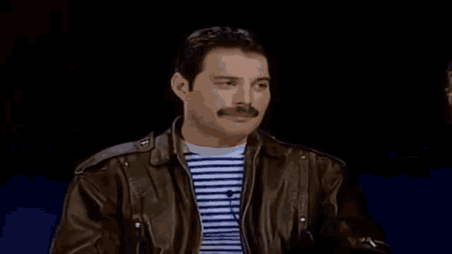 a man with a mustache is wearing a leather jacket and a striped shirt .