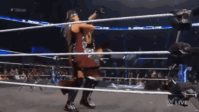 two wrestlers are fighting in a wrestling ring with the words w live on the bottom of the screen
